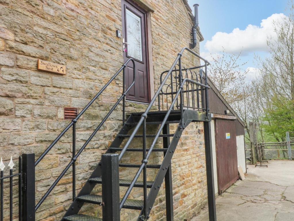 una escalera de metal que conduce a una puerta en un edificio de ladrillo en Swallows Nest, en Macclesfield