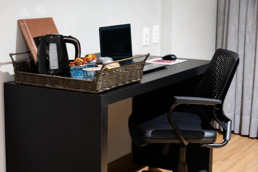 a black desk with a basket of food and a chair at Comfort Suítes Vitória in Vitória
