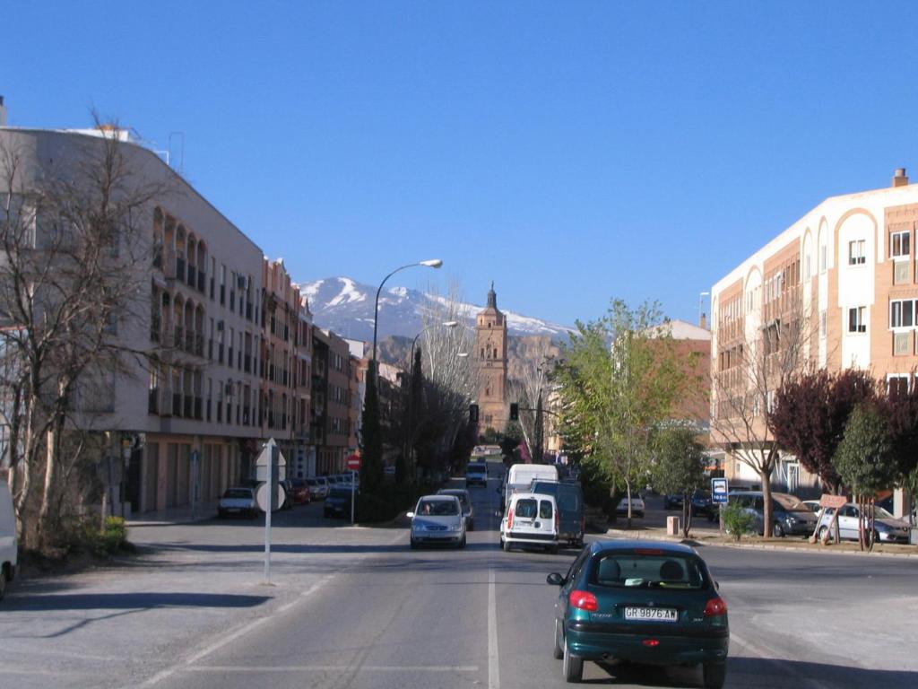 Una calle de la ciudad con coches conduciendo por la calle en Hotel Mulhacen, en Guadix