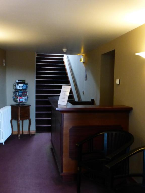 a room with a staircase with a chair and a table at Hotel De France in Pontorson