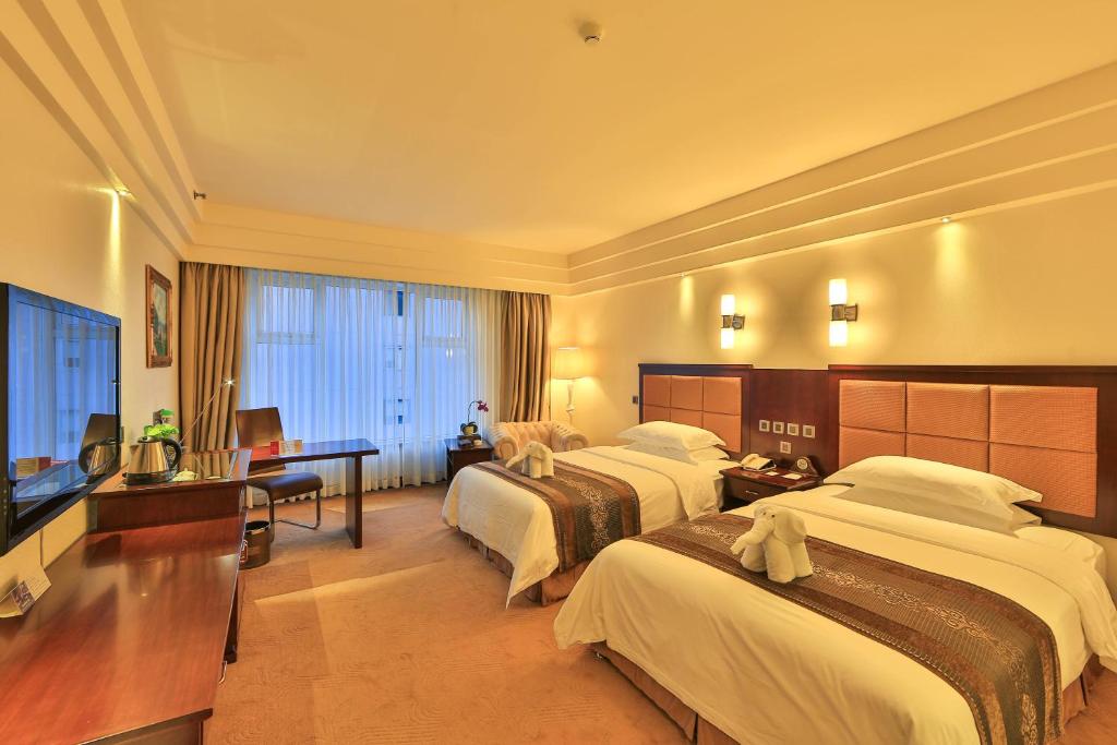 a hotel room with two beds and a television at Ramada Chengdu North in Chengdu
