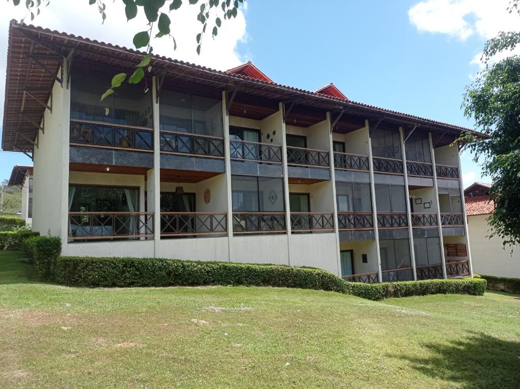 um grande edifício com um relvado em frente em Flat no condomíno Monte Castelo em Gravatá-PE em Bezerros