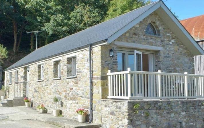 a stone building with a porch and a balcony at Wild Coastal Retreat at Troed Y Rhiw Aberporth in Aberporth