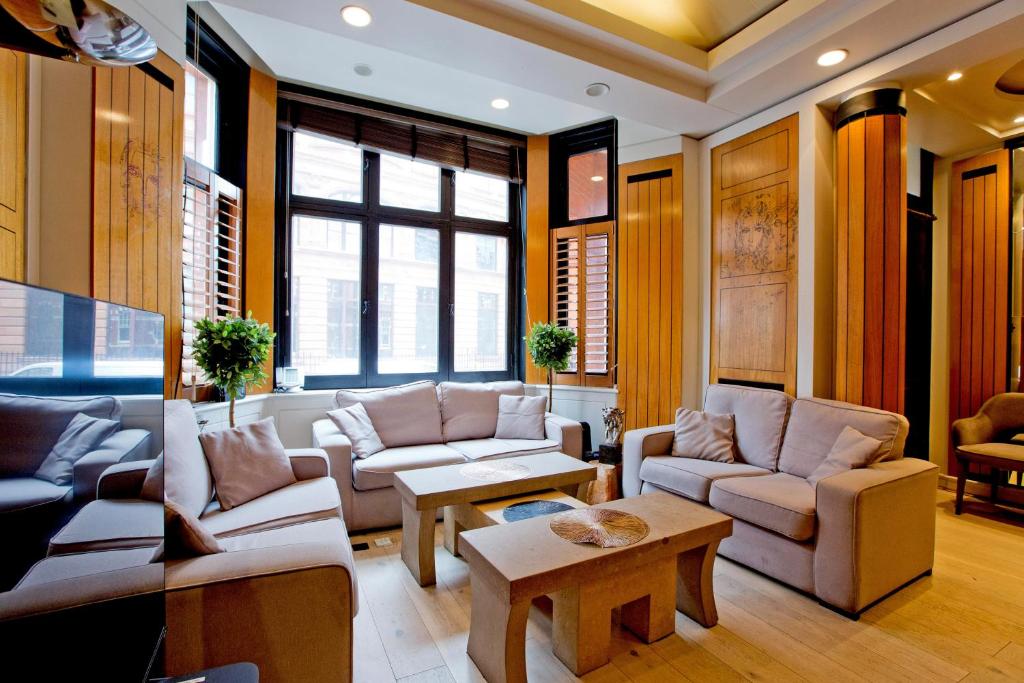 a living room with couches and tables and windows at Harrods Hideaway 3 Bedroom Flat in London