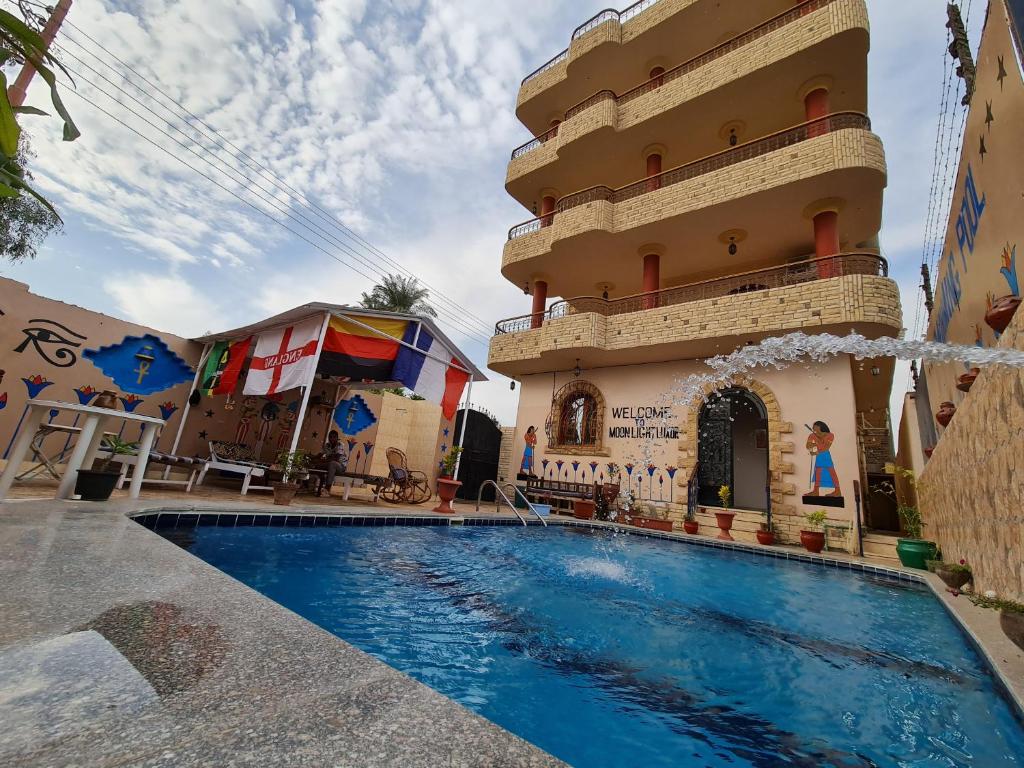 a building with a swimming pool in front of a building at Moonlight Home in Luxor