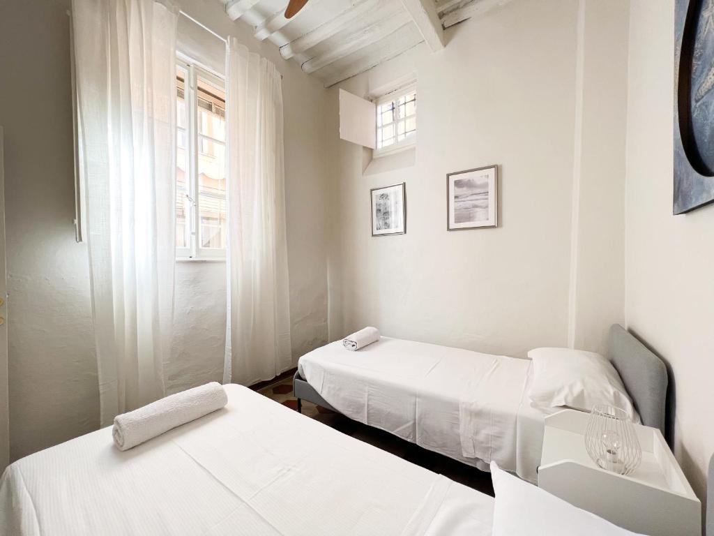 2 łóżka w małym pokoju z białymi ścianami w obiekcie Civico 41 Lucca City Center Apartment w Lukce
