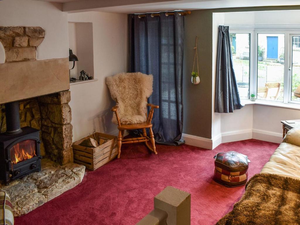 uma sala de estar com lareira e uma cadeira em Ashgrove Cottage em Dudbridge