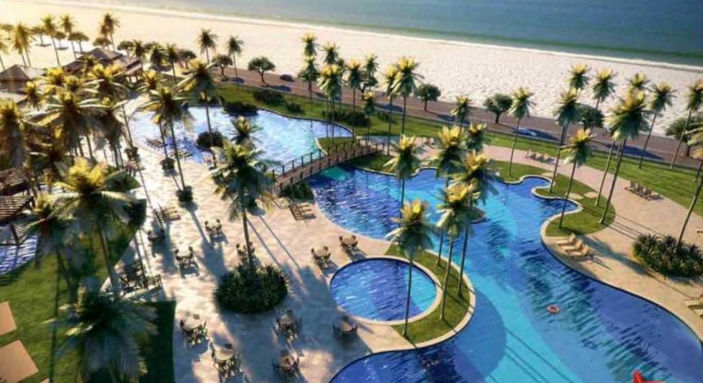 an aerial view of a resort with palm trees and a beach at Golf Ville Resorts Residence 3 Suítes, Porto das Dunas in Aquiraz