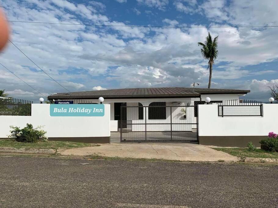 una casa blanca con un letrero que dice Holiday inn azul en Bula Holiday Inn, en Nadi