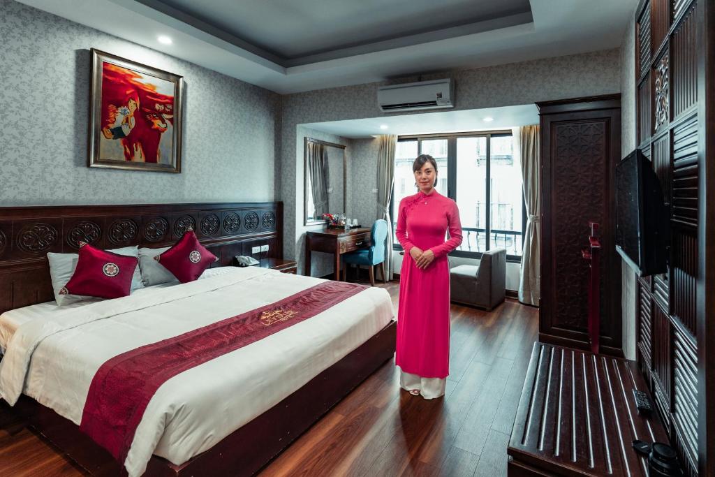 uma mulher num quarto de hotel com uma cama em Lefoyer Hotel em Hanói