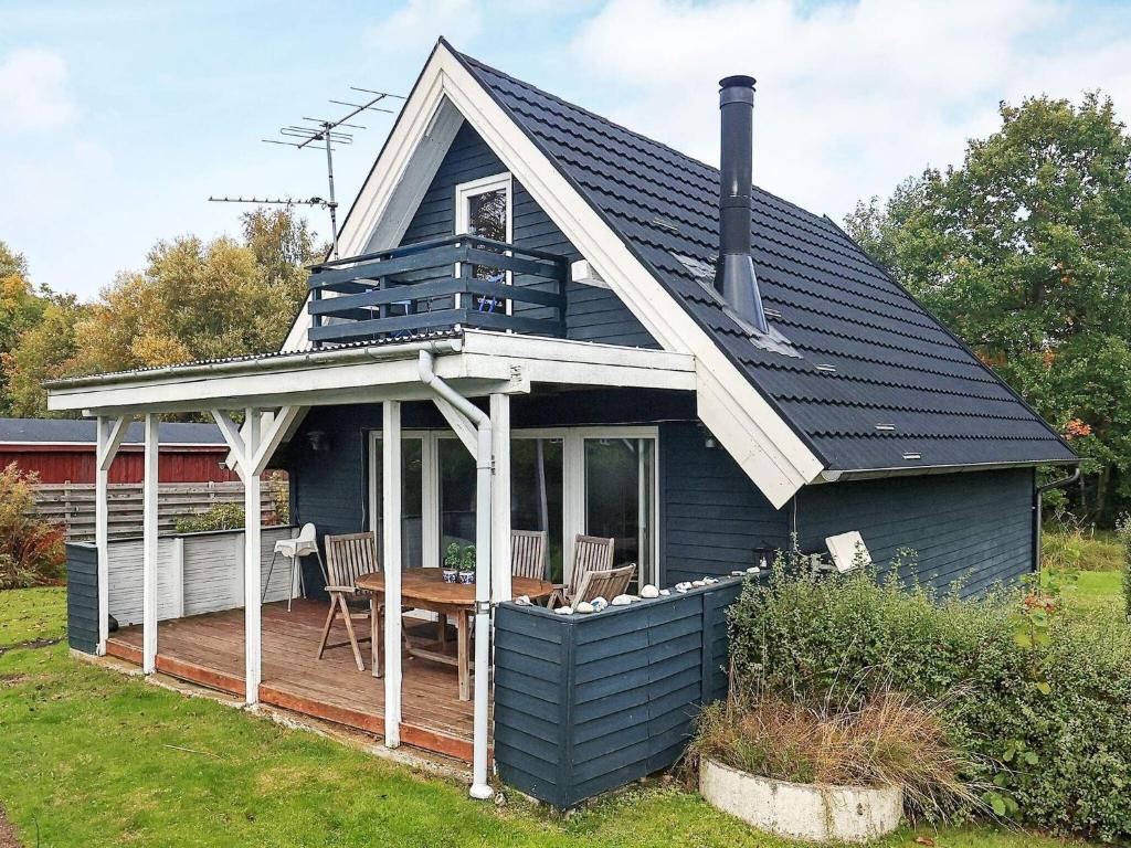 une maison bleue avec une terrasse couverte et une table sur une terrasse dans l'établissement 5 person holiday home in Fr rup, à Tårup