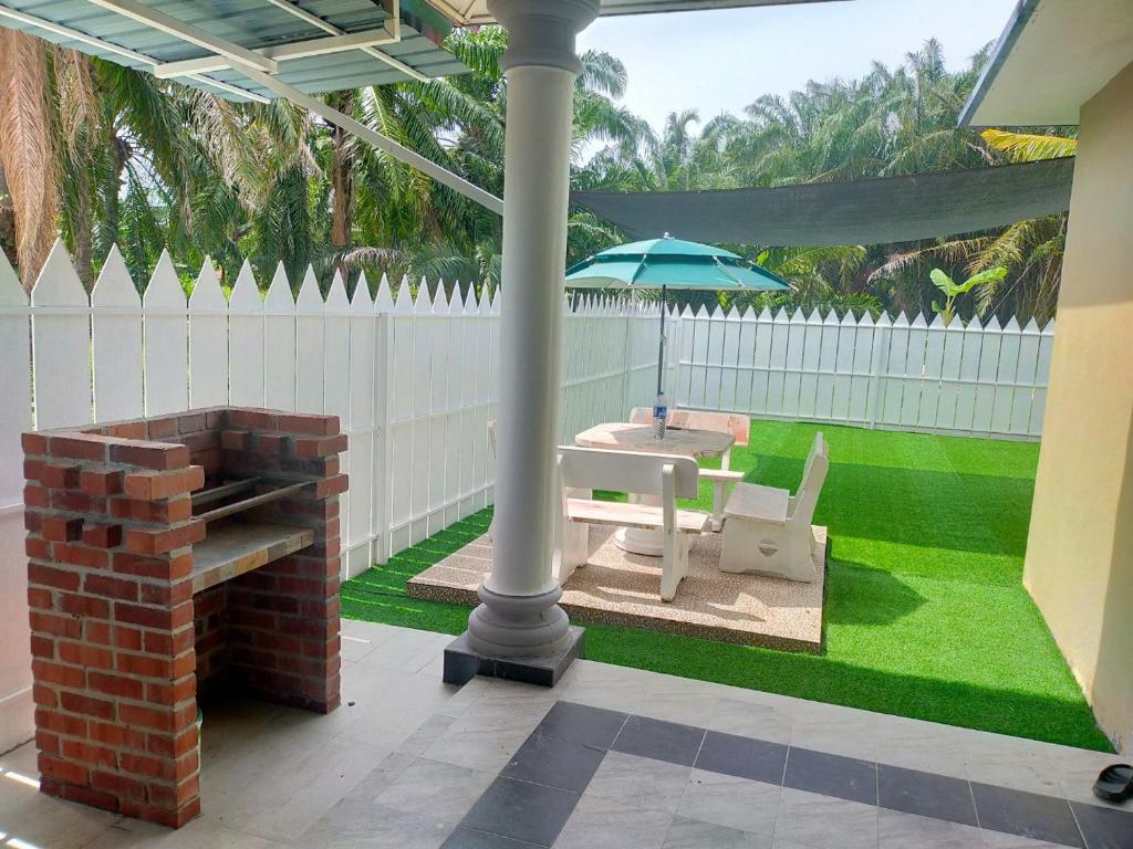 um pátio com um guarda-chuva, uma mesa e um banco em Villa Auliyya - MslimOnly em Kampong Sungai Leman