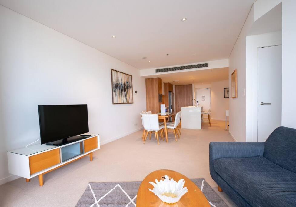 sala de estar con sofá azul y TV en Lvl30 Garden/River views Balcony by Stylish Stays en Brisbane