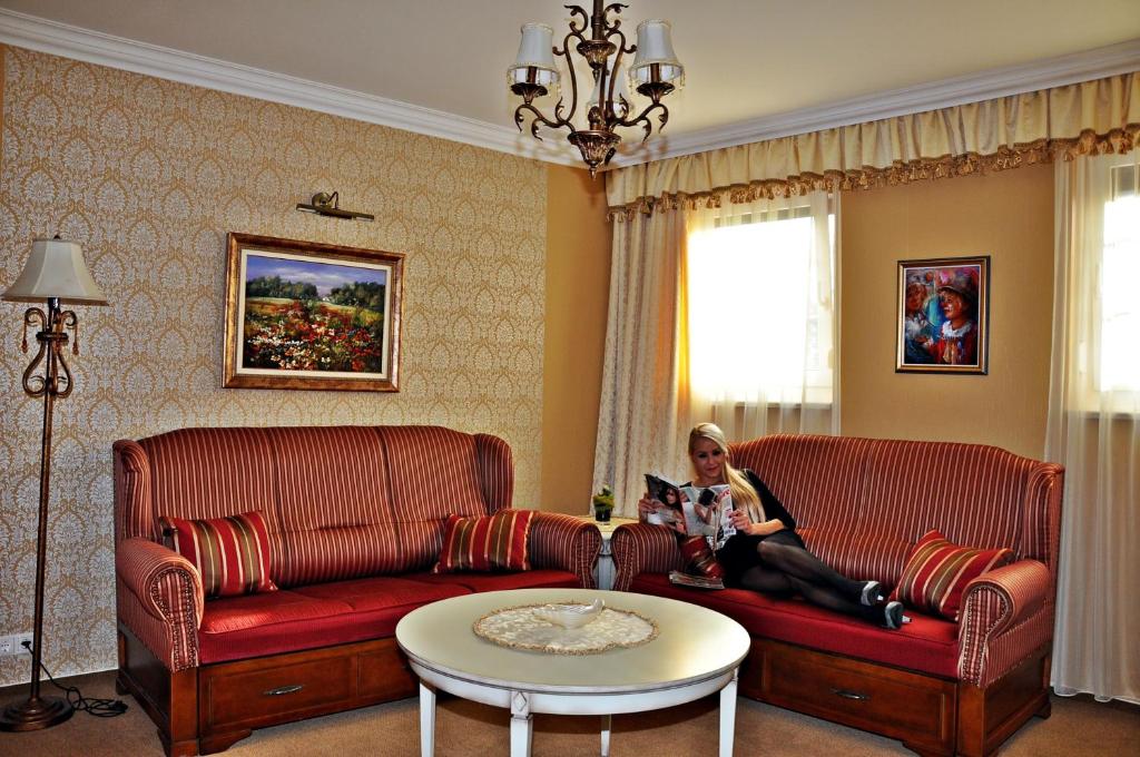 a woman sitting on a couch in a living room at Hotel Villa Classica in Pápa