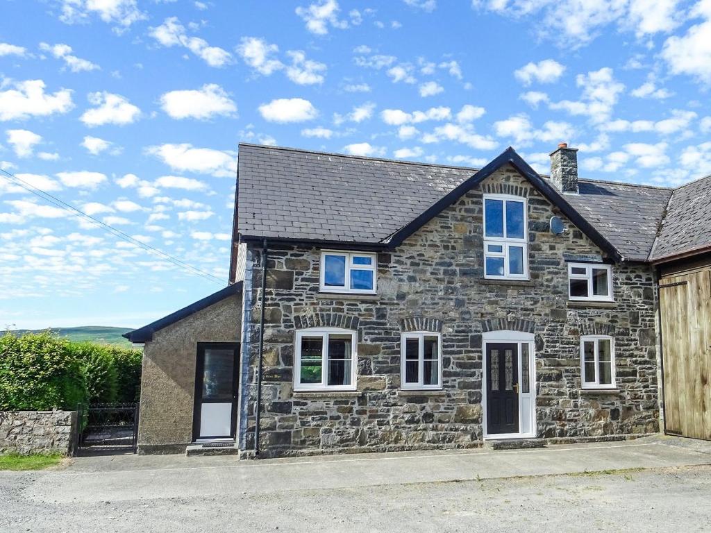 Casa de piedra con ventanas azules y valla en Glan Wye, en Rhayader