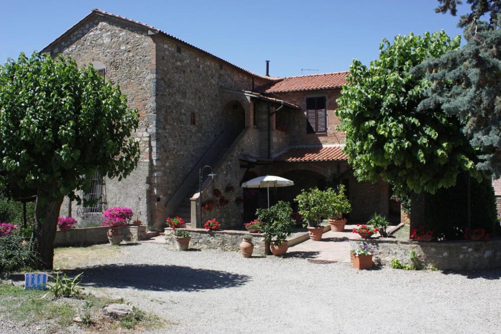a building with a courtyard with flowers and plants at Agriturismo L' Agresto in Casole dʼElsa