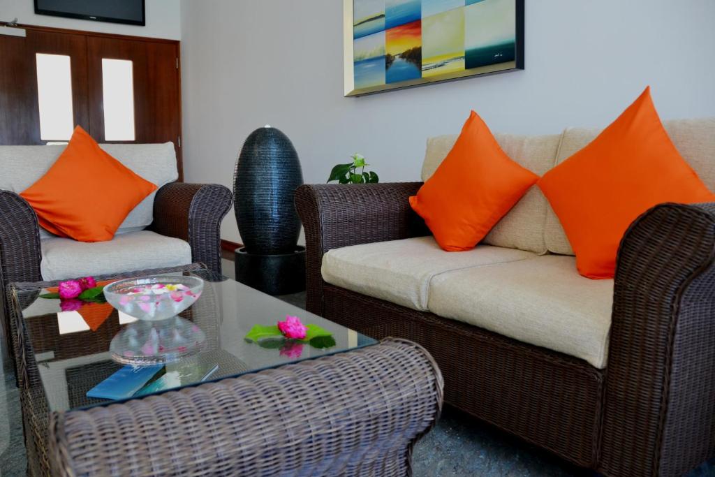 a living room with two couches and a table with orange pillows at The Old School Self-Catering in Baie Sainte Anne