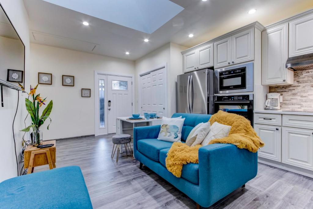 a living room with a blue couch and a kitchen at Marbella Lane - Bright and Cozy Home near SFO in San Mateo