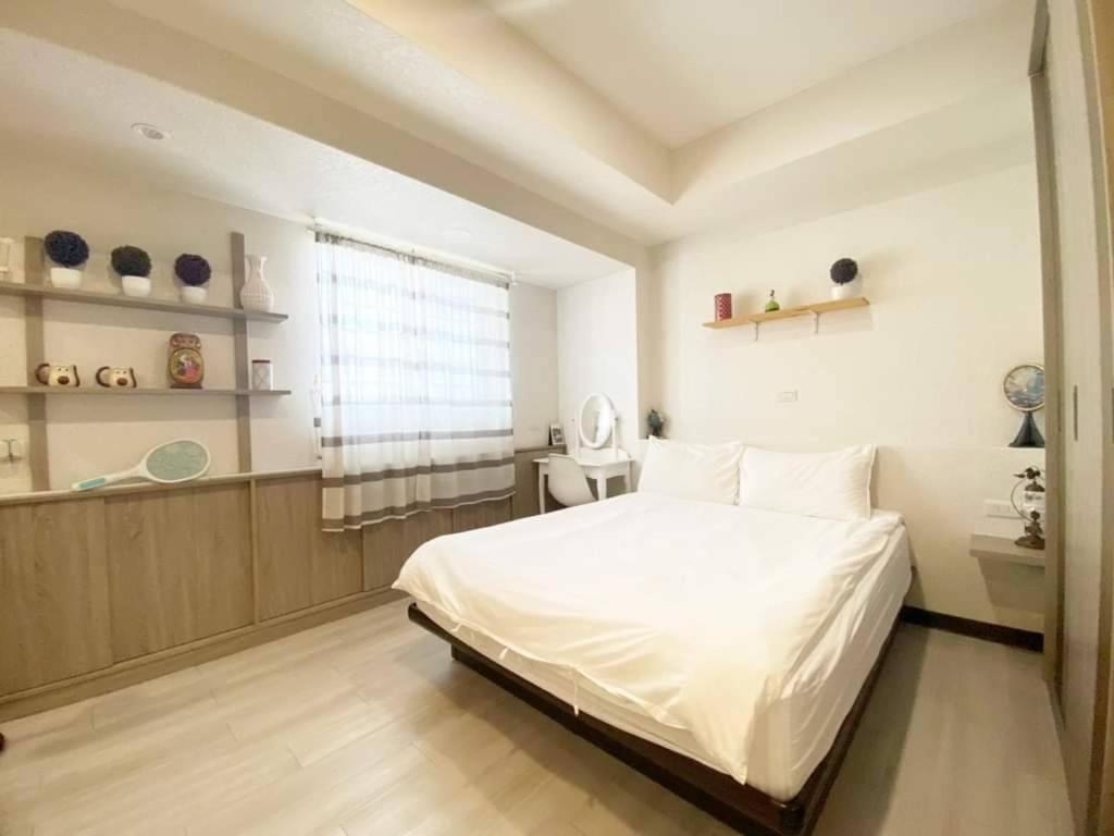 um quarto com uma cama branca e uma janela em Tainan Homestay em Tainan