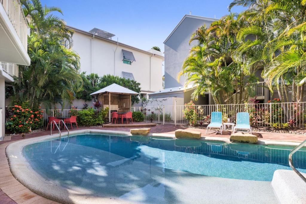 a swimming pool with blue chairs and a building at 7 Riverside in Noosaville