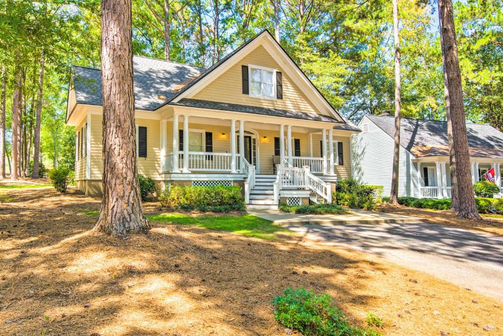 a yellow house with a porch and trees at Stunning Lake Oconee Retreat with Pool Access! in Turnwold