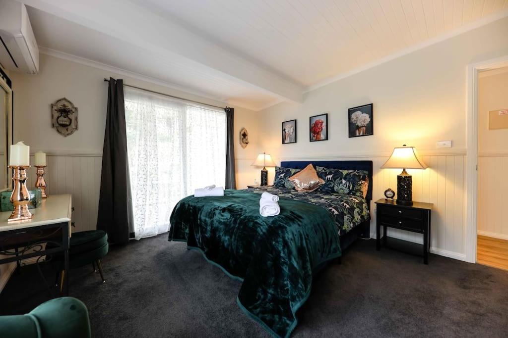 sypialnia z zielonym łóżkiem i oknem w obiekcie Hidden Gem ~ Luxury Cottage near Lake Daylesford w mieście Daylesford
