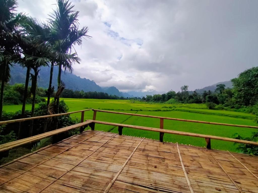 a wooden deck with a view of a green field at Phoxay Ngam Resort in Vang Vieng