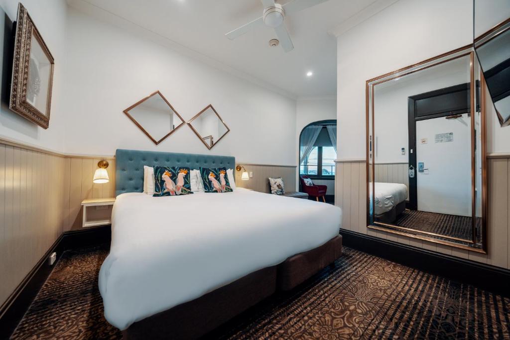 Cette chambre comprend un grand lit et un miroir. dans l'établissement Cremorne Point Manor, à Sydney