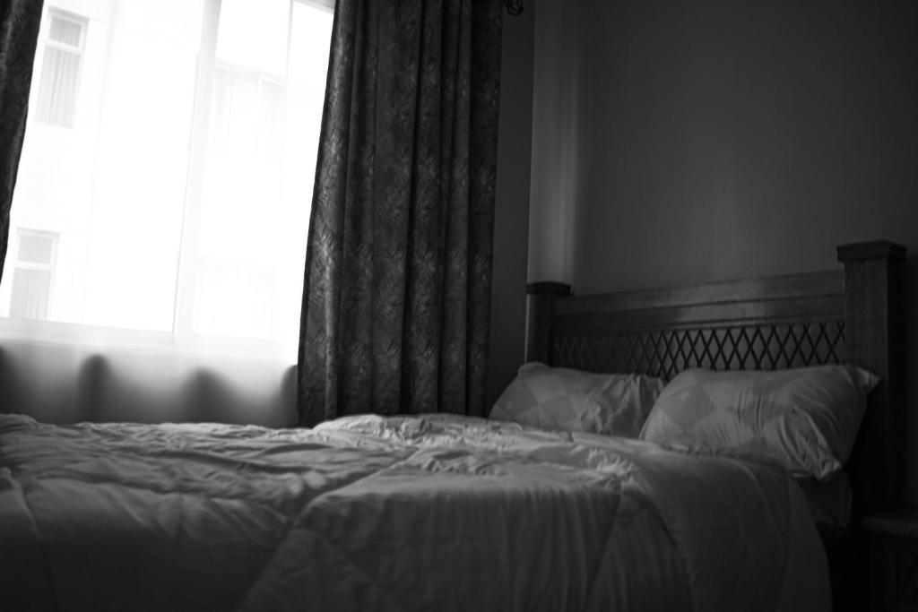 a black and white photo of a bed with a window at One bedroom apartment in Nairobi