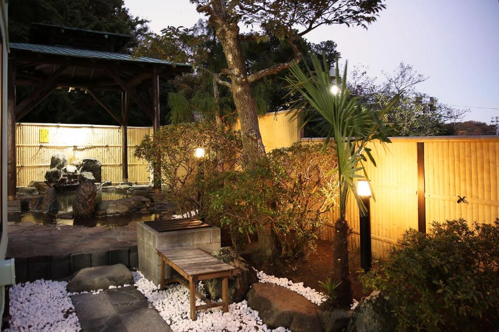 um jardim com um banco, uma árvore e uma cerca em Harukaze no Yado em Iwaki