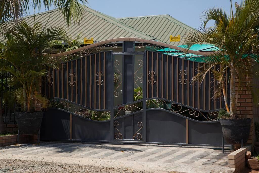 a black gates with palm trees in front of a house at Netflix/WI-FI, 3 bedroom and free parking in Livingstone