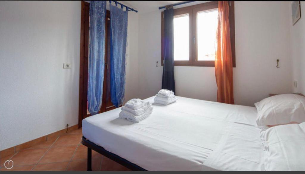 Un dormitorio con una cama blanca con toallas. en Airport at 25 min ByWalk-Big Port 10 min by bus-Bus&CommCenter 1 min by walk - 1 min by walk to bus to city and beaches 1 min by walk to touristic port-entire Apartement with 3 indipendent rooms Air cond&WIFI&washMachine till 6 pex AZZURRO en Olbia