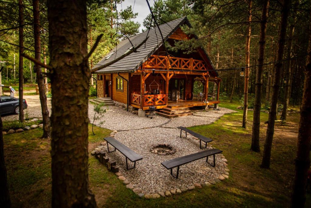 a cabin in the woods with benches in front of it at Łosia Chata in Grzybowce