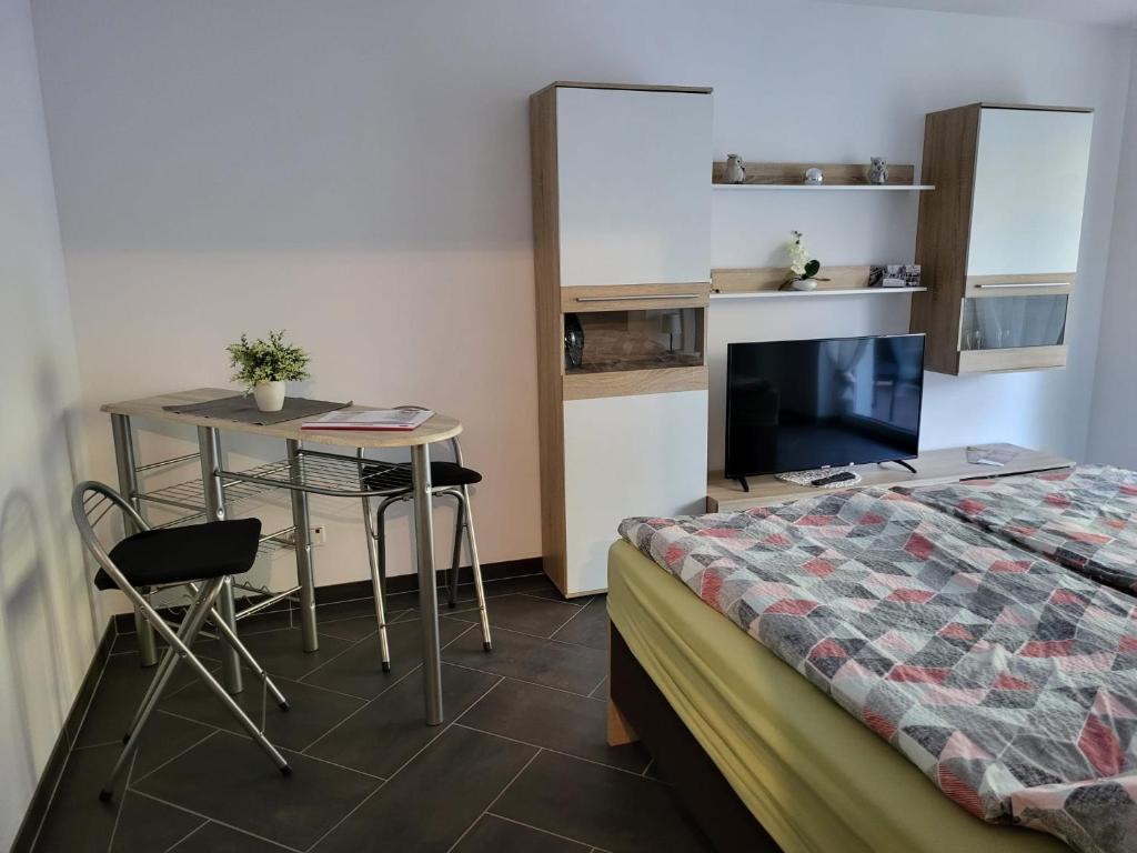 een slaapkamer met een bed, een tafel en een bureau bij Gästewohnung 1 in Oschersleben