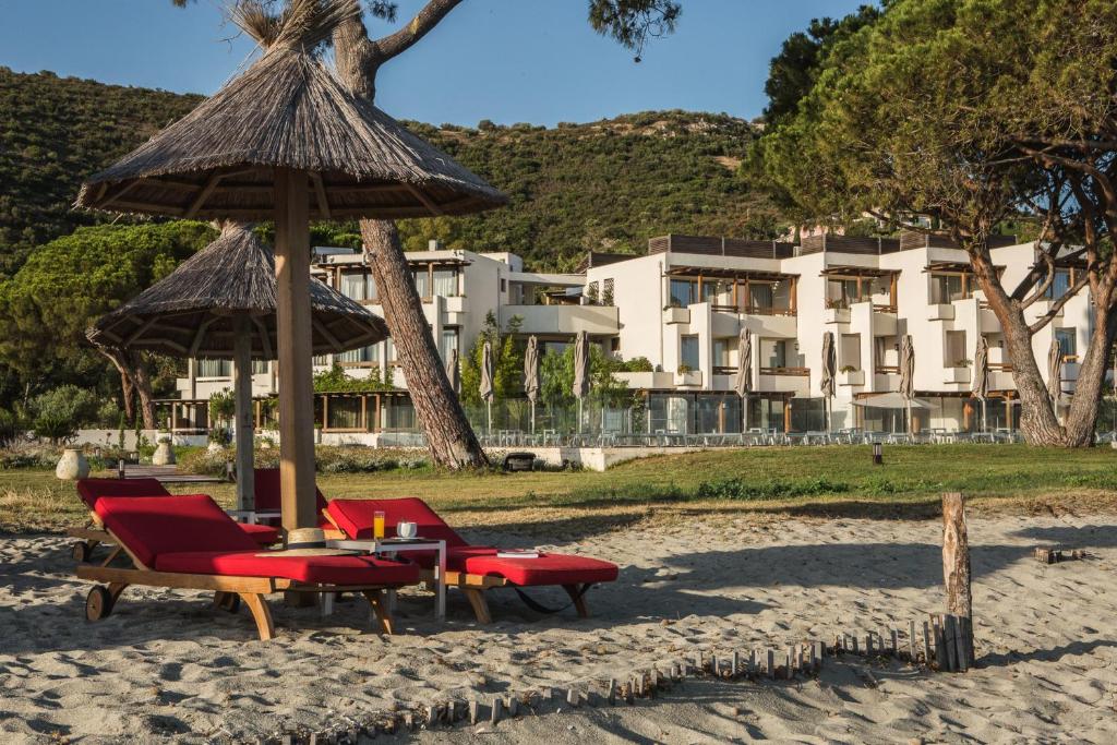 a group of chairs and an umbrella on the beach at Hôtel La Roya in Saint-Florent
