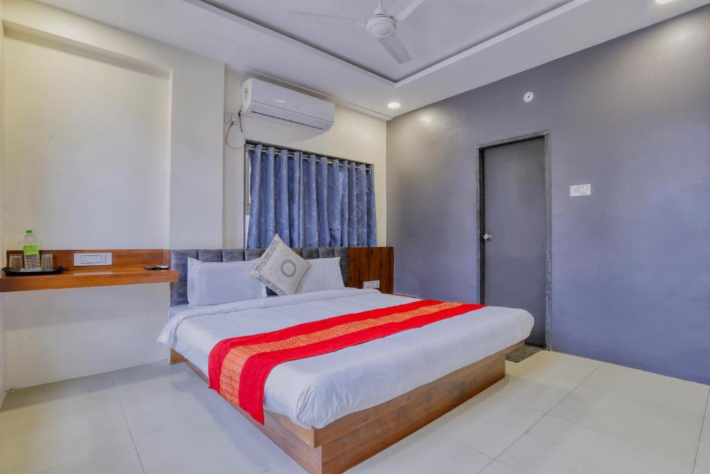 a bedroom with a bed with a red and white blanket at Hotel Kumar Atithi Nivas in Indore