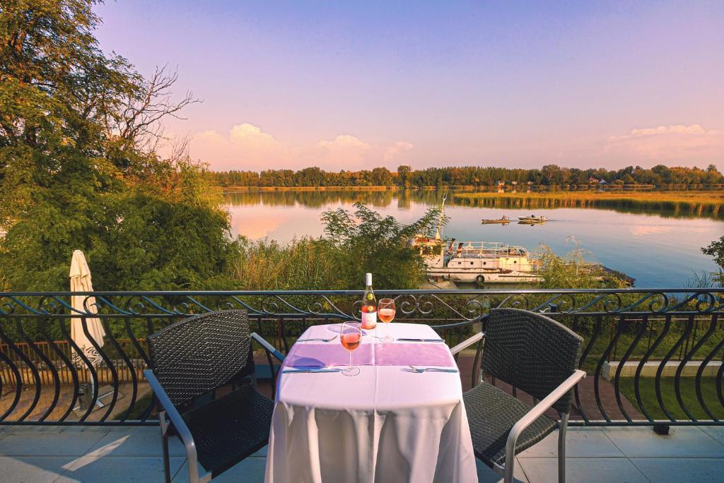 a table on a balcony with a view of a lake at Mártoni Villa in Szigetszentmárton