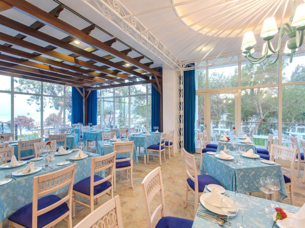 a dining room with blue tables and chairs and windows at Sherwood Exclusive Kemer - Kids Concept in Kemer