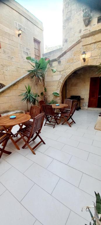 an outdoor patio with wooden tables and chairs at Ta Majsi farmhouse with indoor heated pool in San Lawrenz