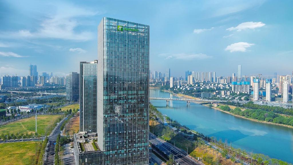 長沙市にあるHoliday Inn Changsha Malanshan, an IHG Hotelの川の横の高層ビル