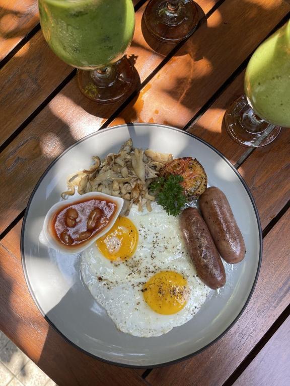a plate of food with eggs and sausage on a table at The Merchant in Galle