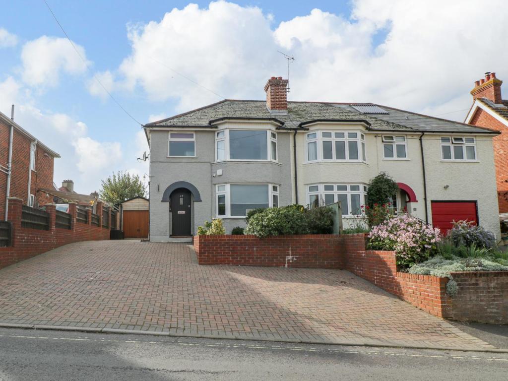 a white house with a brick driveway at Curlew Cottage in Lymington
