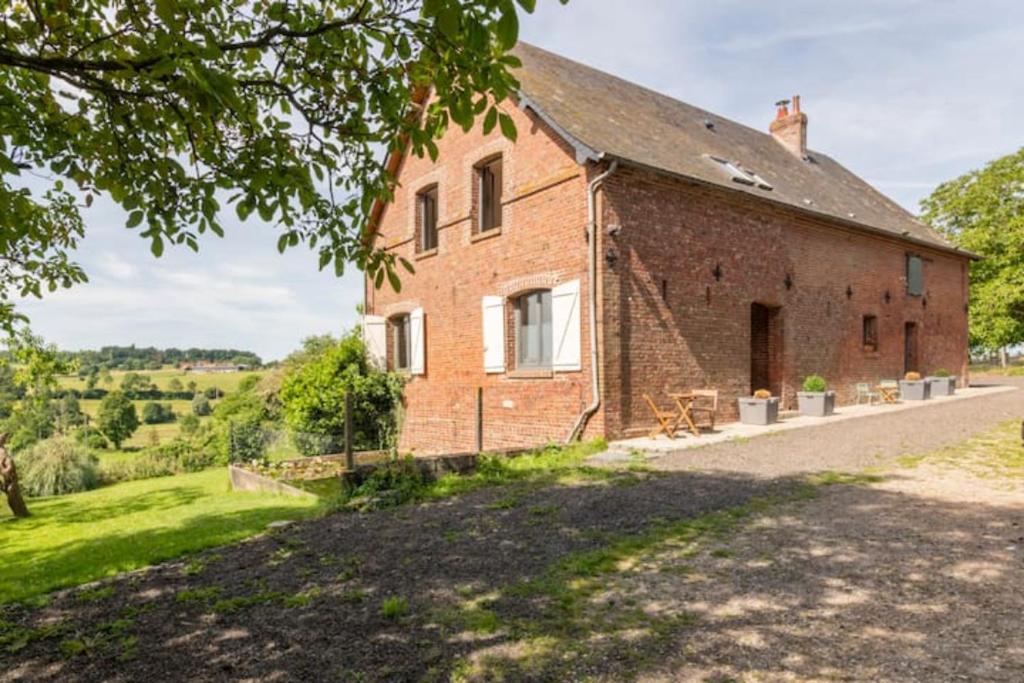 uma antiga casa de tijolos com vista para um campo em Normandy holiday cottage 'Le Papillon' em Neufchâtel-en-Bray