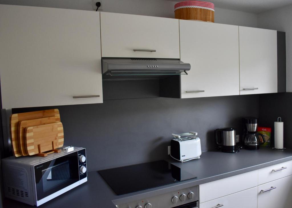 uma cozinha com armários brancos e um micro-ondas em Kontorhaus Senftenberg em Senftenberg
