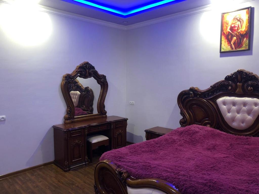 a bedroom with a bed with a purple blanket and two mirrors at Yerevan Qanaqer House in Yerevan