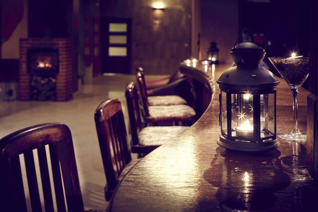Dimly lit wooden bar with lantern centerpiece, candles, and high stools, cozy intimate mood.
