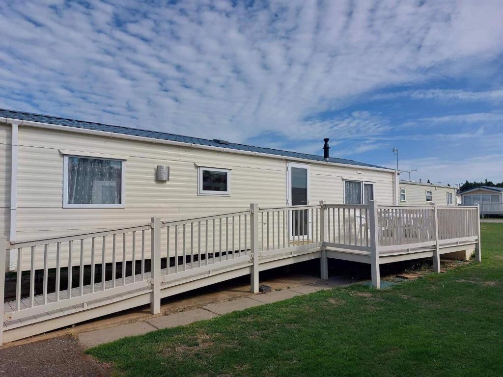 a white mobile home with a wooden deck at 2 bedroom caravan in hunstanton free wi-fi in Hunstanton