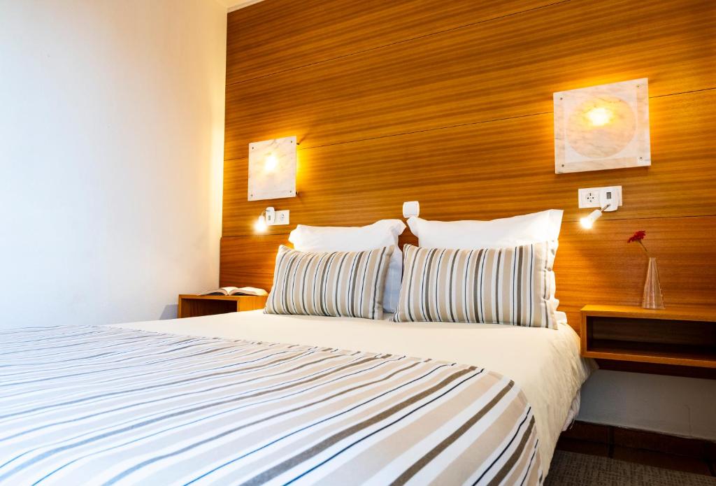 a bedroom with a large bed with a wooden headboard at Hotel Apartamento Porto Covo in Porto Covo