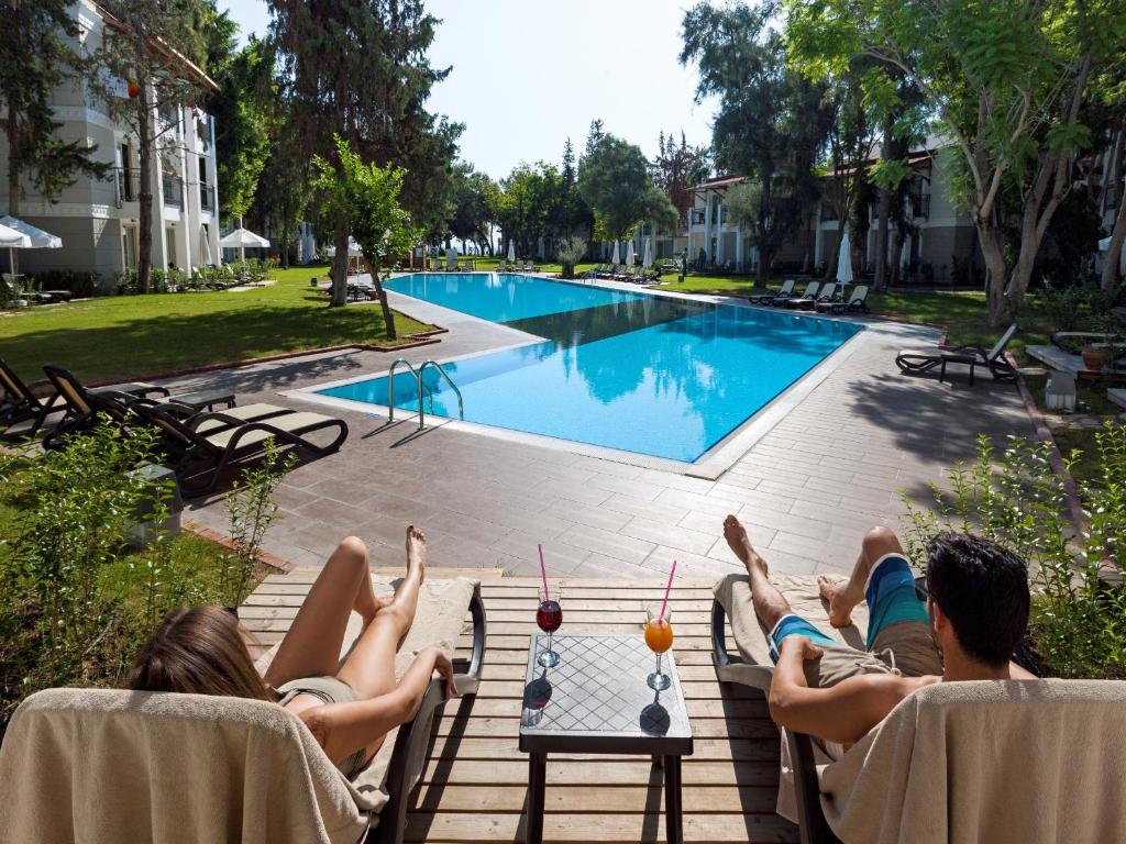 a group of people laying on a table near a pool at Sherwood Exclusive Kemer - Kids Concept in Kemer