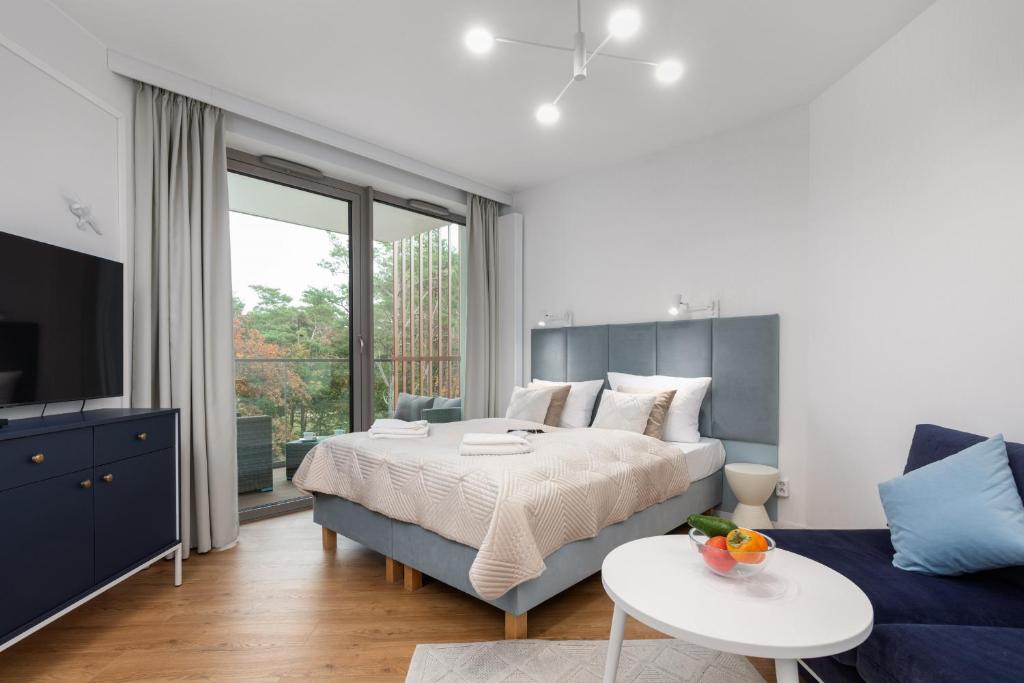 sypialnia z łóżkiem, telewizorem i kanapą w obiekcie Apartments Mazowiecka Pobierowo by Noclegi Renters w Pobierowie